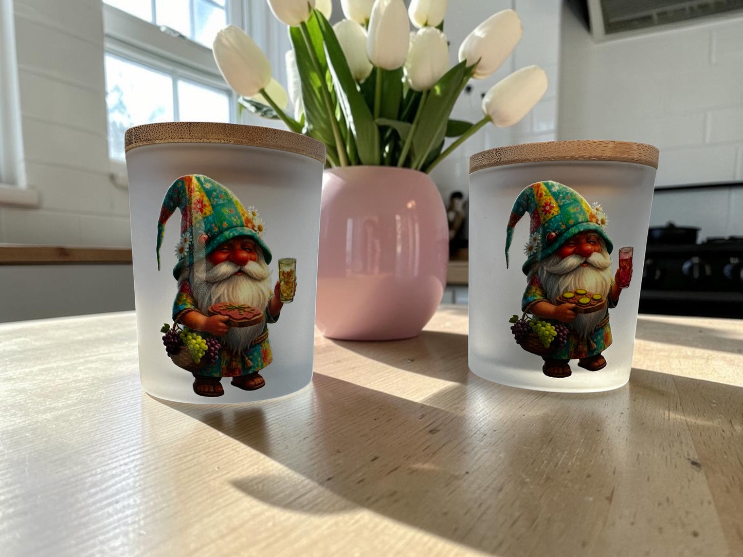 Zwei gefrostete Gnodel-Windlichter nebeneinander auf einem hellen Holztisch. Das linke Glas zeigt den Pfälzer Wichtel mit einer gelben Rieslingschorle, das rechte Glas den Wichtel mit einer roten Weißherbstschorle. Beide Gläser sind mit einem passenden Holzdeckel verschlossen.