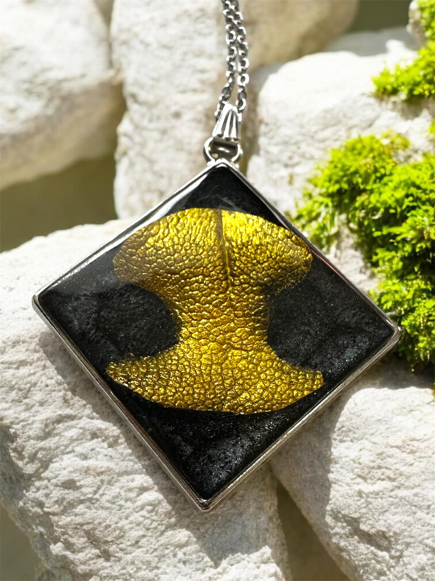 Quadratischer Gedenkschmuck Anhänger mit goldenem Hundenasen-Abdruck auf schwarzem Grund.
