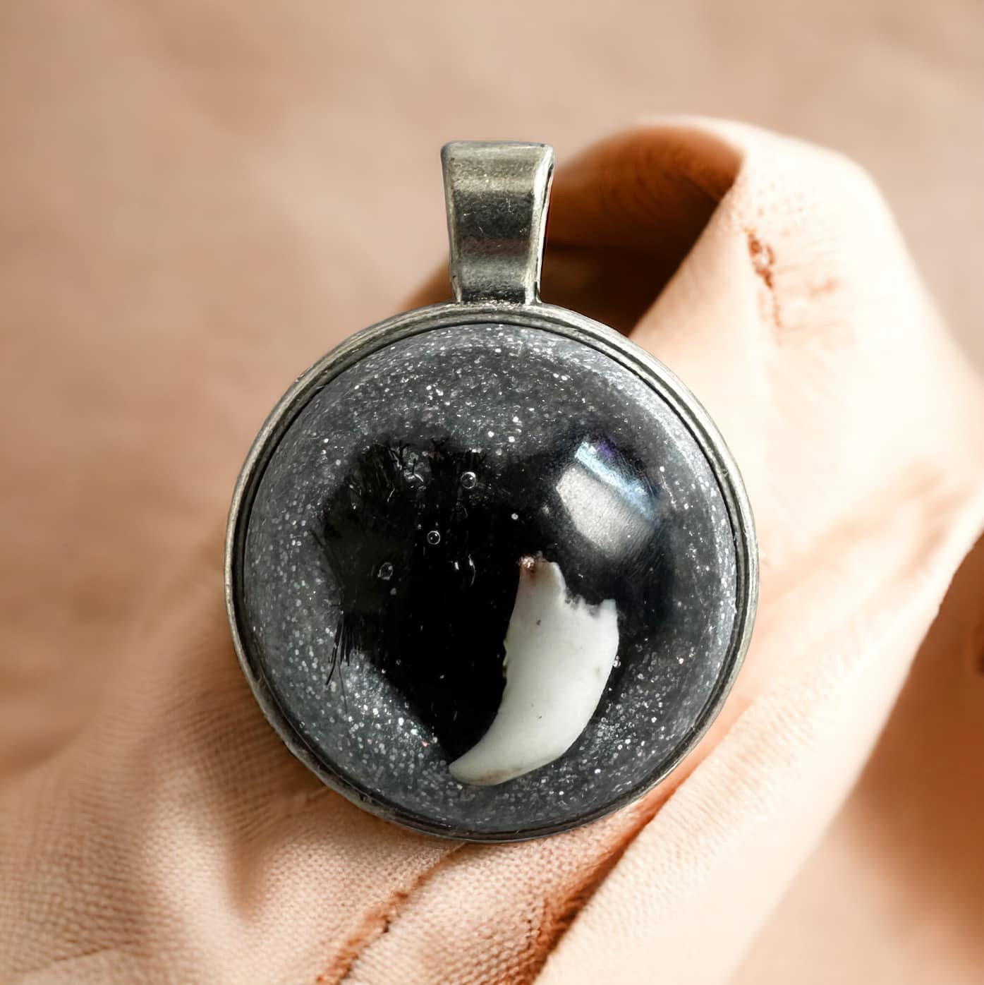 Runder Gedenkschmuck Anhänger mit einem eingearbeiteten Milchzahn in glitzerndem Epoxidharz.