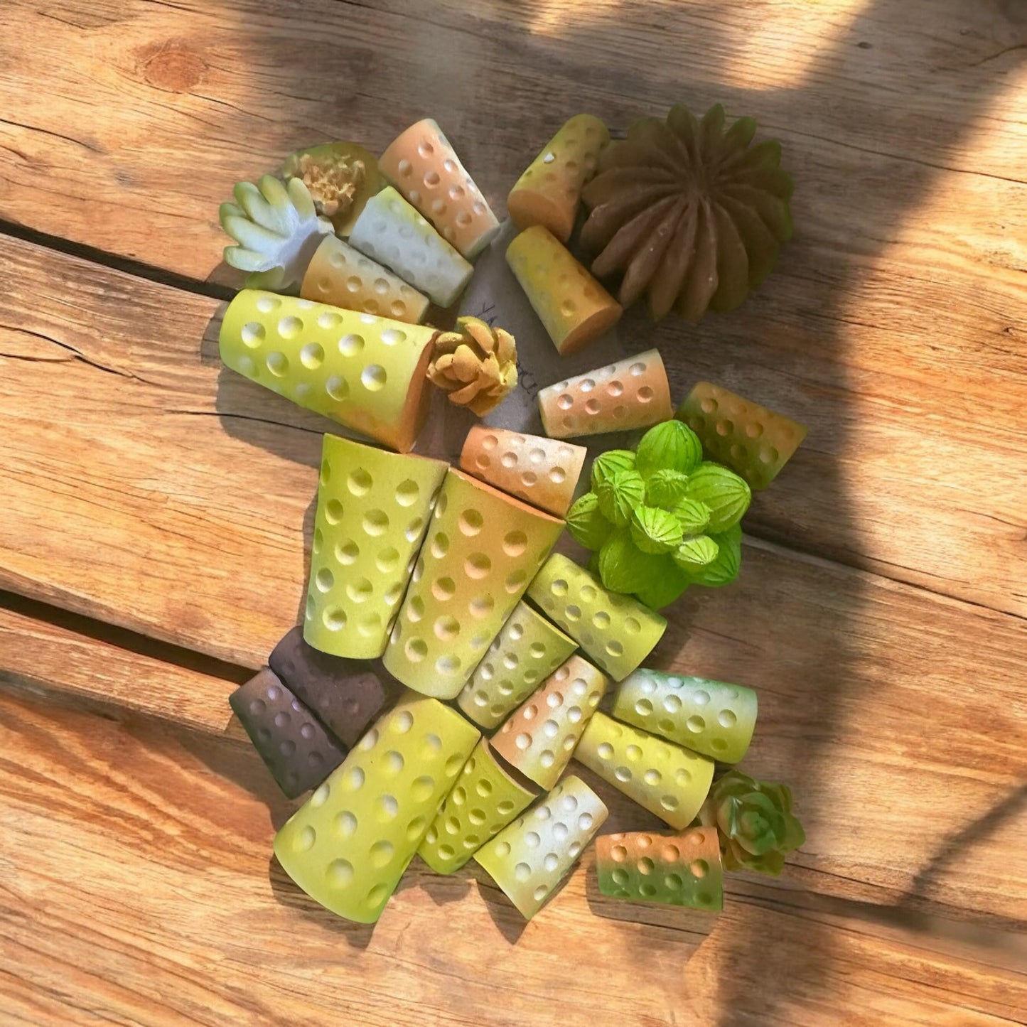 Draufsicht auf eine Sammlung verschiedenfarbiger, bedufteter Dubbegläser und kleiner künstlicher Sukkulenten auf einem rustikalen Holzhintergrund. Dufte Geschenkidee für alle Pfalzkinder und Pfalz-Liebhaber