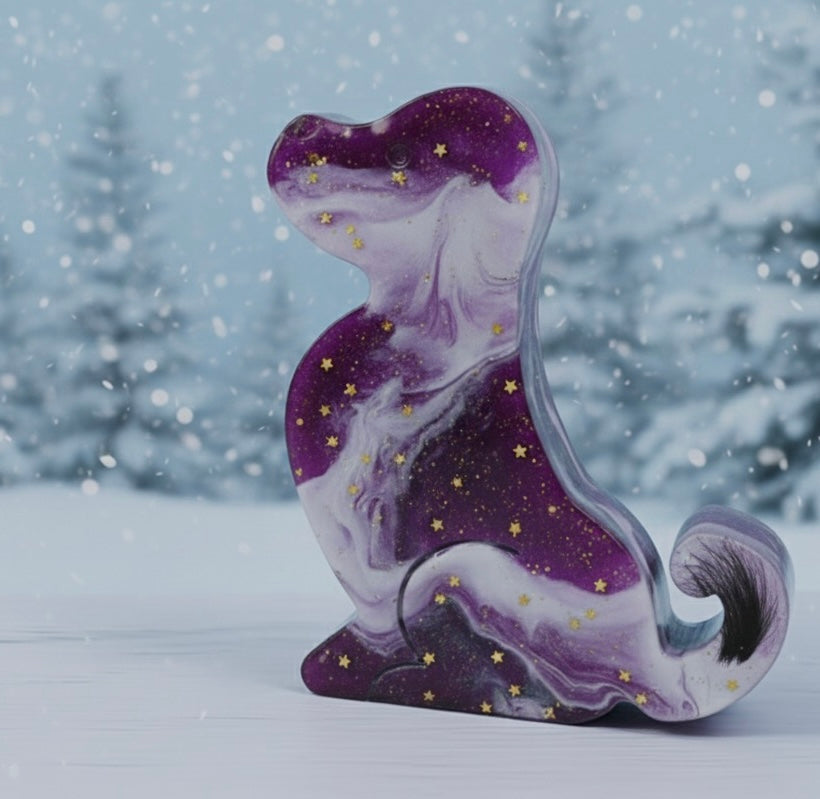 Lila-violette Gedenk-Figur in Hundeform aus Epoxidharz mit weißer Marmorierung, goldenen Sternen und einer eingearbeiteten dunklen Tierhaar-Locke im Schwanzbereich.