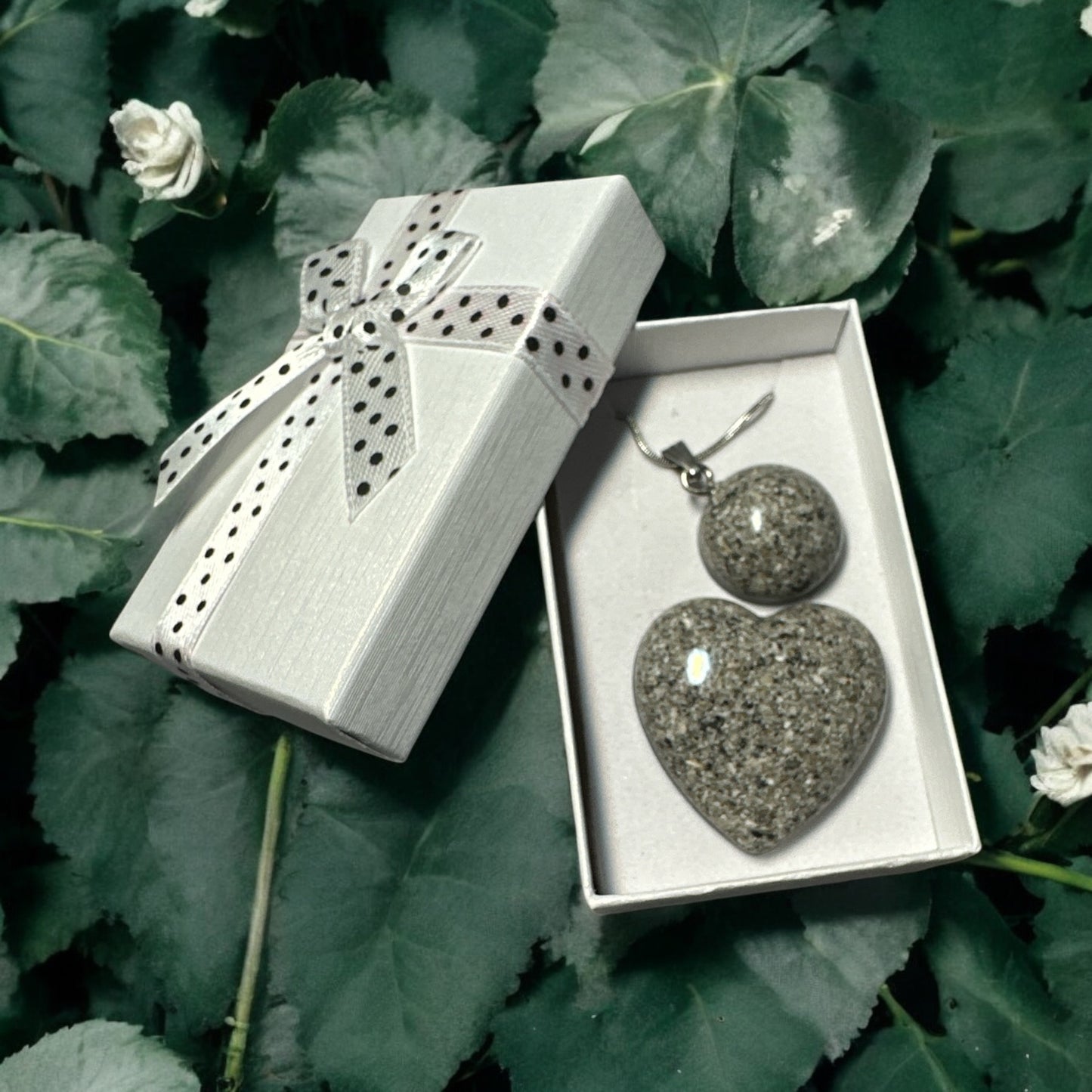 Runder Gedenkschmuck Anhänger aus Epoxidharz mit eingearbeiteter Asche.
Herzförmiger Gedenkstein aus dunklem Epoxidharz mit eingearbeiteter Asche.