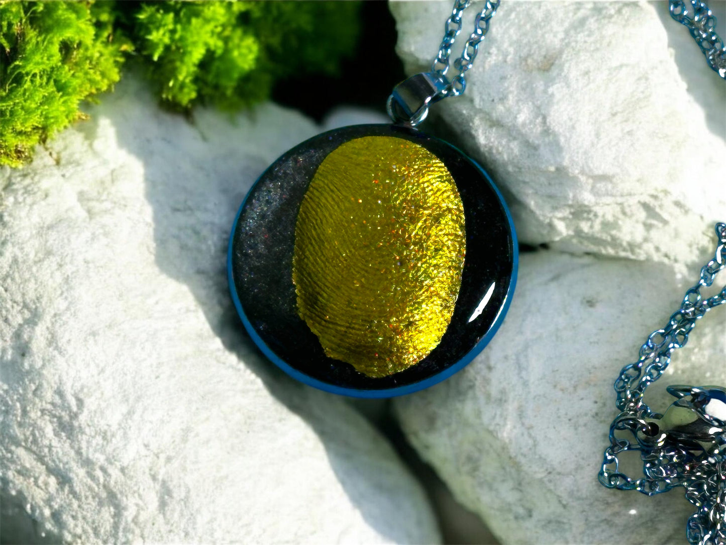 Detailaufnahme eines Gedenkschmuck nhängers mit goldener Struktur und Fingerabdruck-Optik