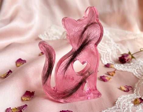Rosa Gedenk-Figur in Katzenform aus Epoxidharz mit eingearbeitetem dunklen Tierhaar als individuelles Erinnerungsstück.