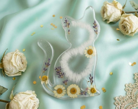 Helle Gedenk-Figur Katze aus Epoxidharz mit eingearbeiteten echten Trockenblumen, Gänseblümchen und weißem Tierhaar.