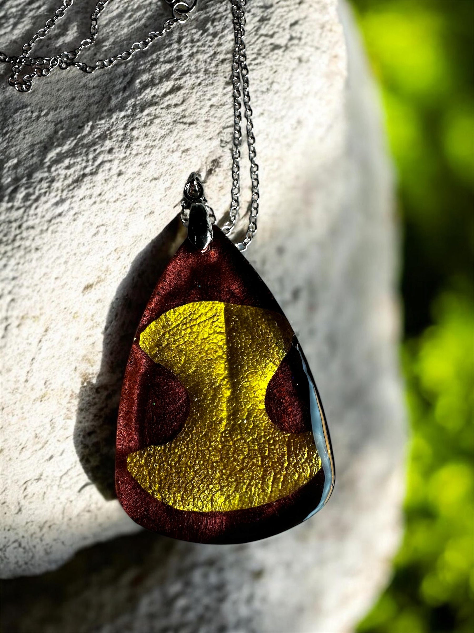 Gedenkschmuck Anhänger in Tropfenform mit goldenem Hundenasen-Abdruck an einer silbernen Kette.