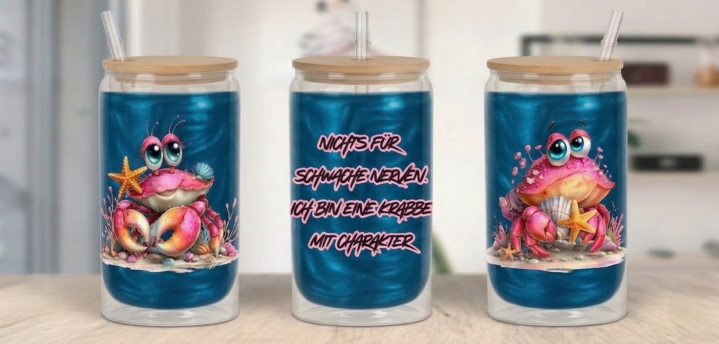 Drei Tumbler mit Bambusdeckeln und Strohhalmen, gefüllt mit einem intensiv schimmernden blauen Getränk. Die Becher zeigen niedliche, rosafarbene Krabben-Illustrationen mit großen Augen und Seesternen. Das mittlere Glas trägt den frechen Spruch: „Nichts für schwache Nerven. Ich bin eine Krabbe mit Charakter