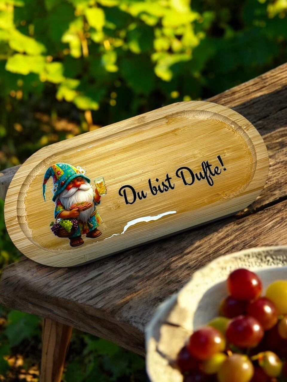 Handgefertigtes Pfälzer Deko-Tablett aus Bambus mit dem Pfälzer Dubbe-Wichtel-Motiv ‚Du bist Dufte!‘. Brillante UV-DTF Grafik mit glänzender Hartharz-Schutzschicht, fotografiert in sonniger Weinberg-Atmosphäre. originelle Geschenkidee und Pfalzdeko