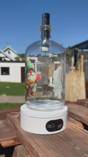 360-Grad-Ansicht der Pfälzer Flaschenlampe mit Dubbewichtel Gnodel vom Wingert. Das Video zeigt die beleuchtete Dekoflasche auf einem Drehteller im Garten, um das Wichtel-Motiv, die Lichterkette und das hochwertige Glas-Design von allen Seiten zu präsentieren.