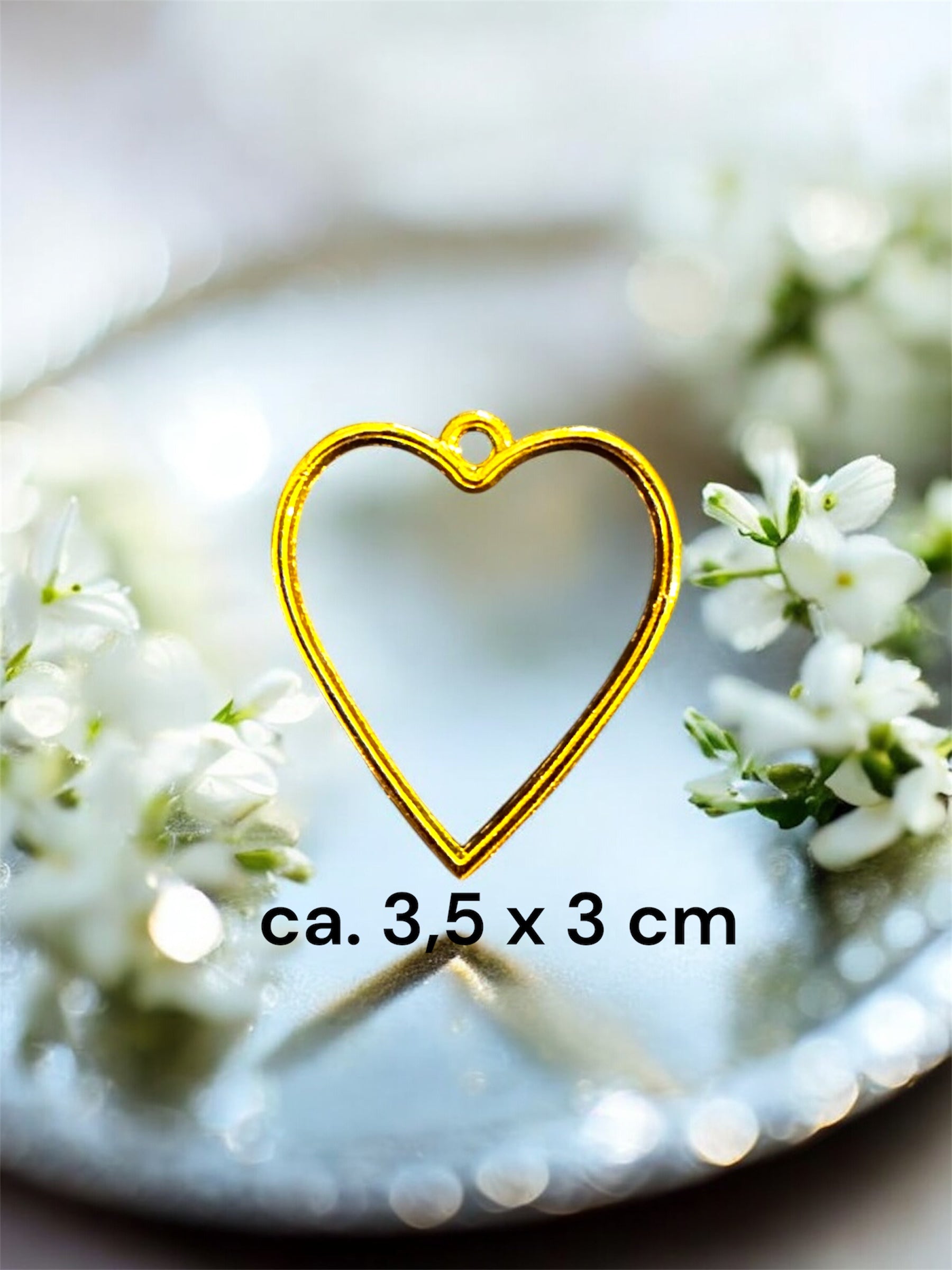 Größenvergleich einer herzförmigen Gedenkschmuck Fassung in Gold mit den Maßen ca. 3,5 x 3 cm.