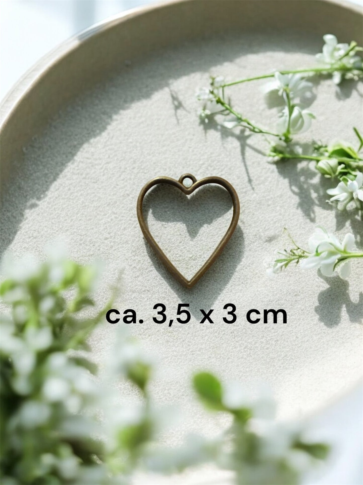 Größenvergleich einer herzförmigen Gedenkschmuck Fassung aus Messing mit den Maßen ca. 3,5 x 3 cm.