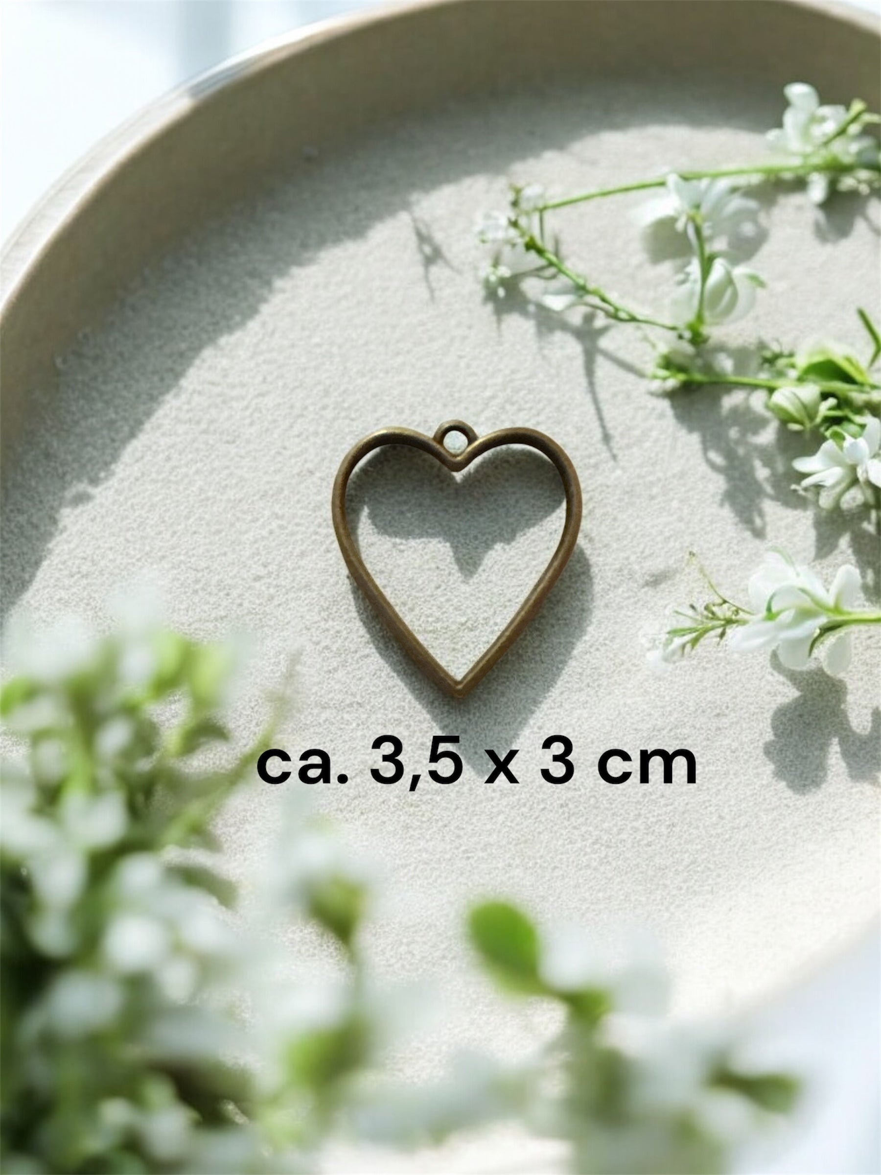 Größenvergleich einer herzförmigen Gedenkschmuck Fassung aus Messing mit den Maßen ca. 3,5 x 3 cm.