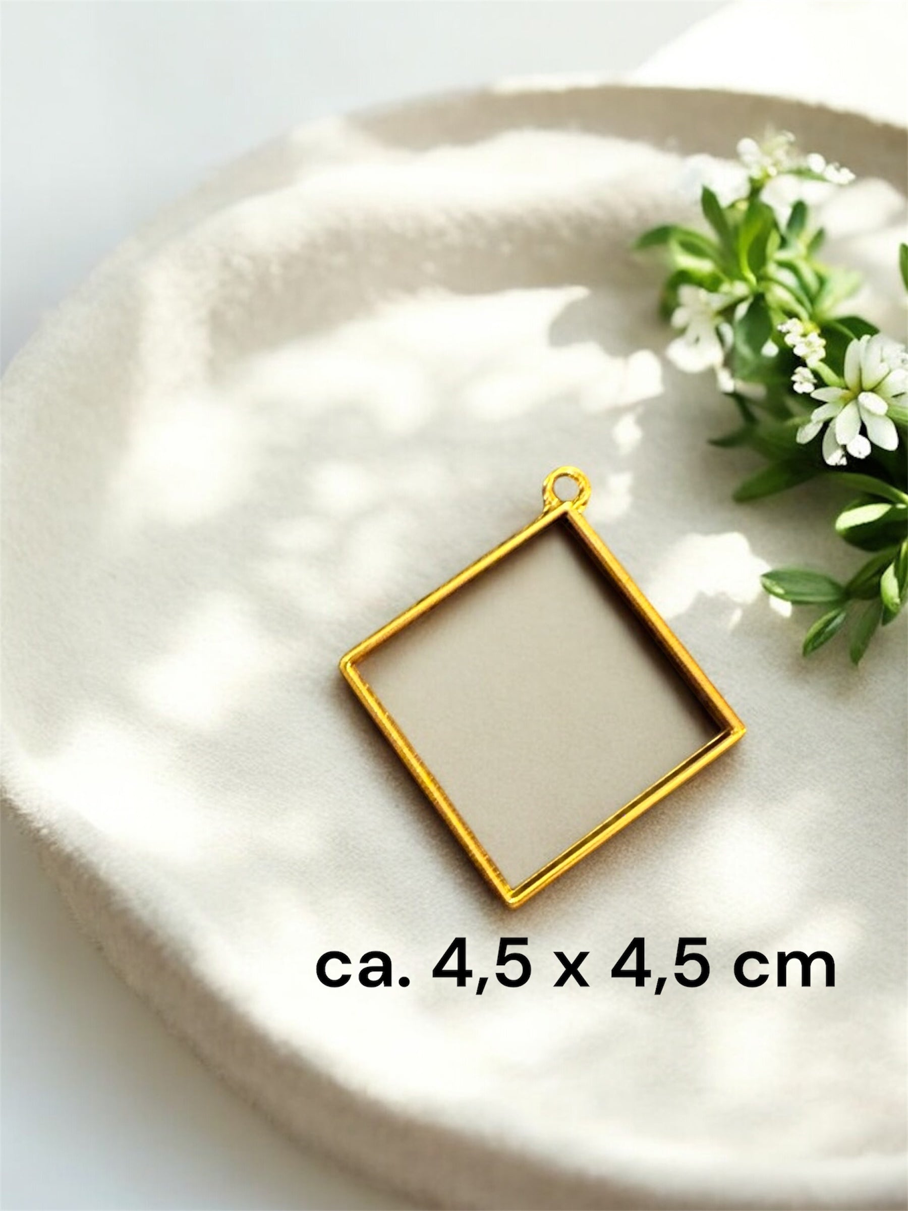 Größenvergleich einer großen quadratischen Gedenkschmuck Fassung in Gold mit den Maßen ca. 4,5 x 4,5 cm.