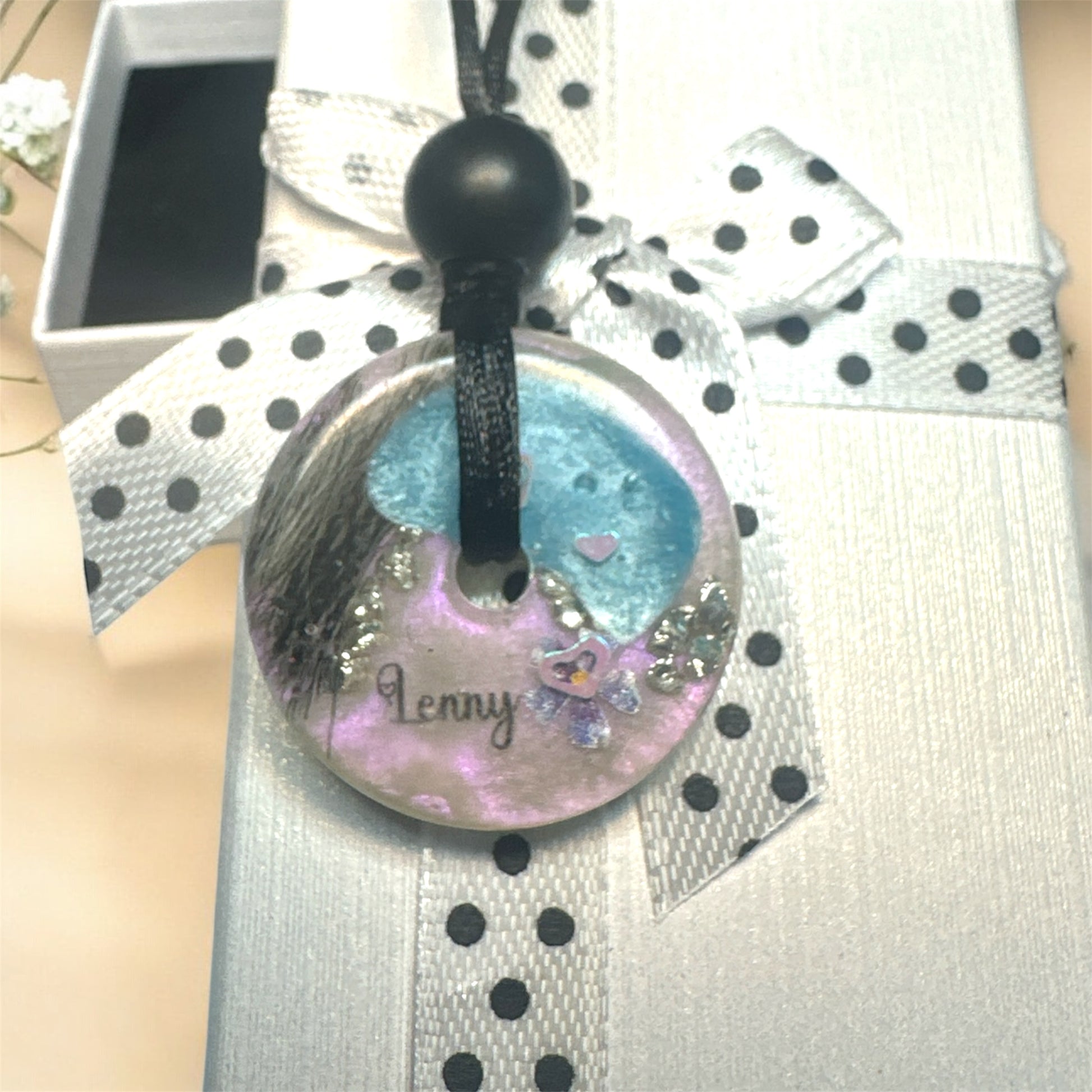 Runder Gedenkschmuck Anhänger in Donut-Form mit dem Namen Lenny, Tierhaar-Einarbeitung und lila-blauen Farbakzenten.
